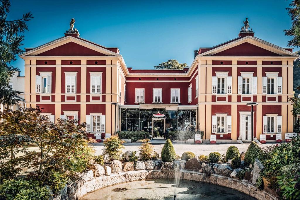 a large building with a fountain in front of it at Hotel Villa Madruzzo in Trento