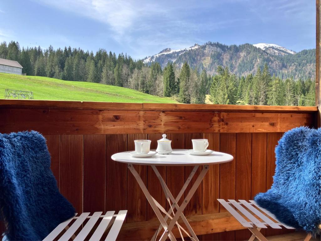 a table and chairs on a porch with a view at Krähenberg am Rande der Wildnis in Sibratsgfäll