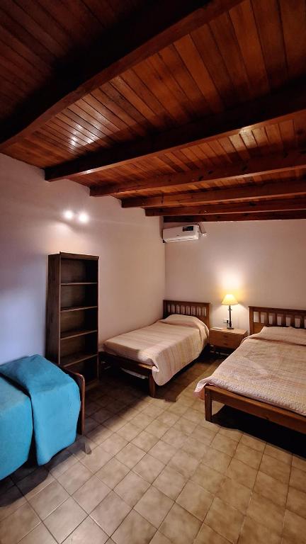 a bedroom with two beds and a wooden ceiling at Casa Kuntur in Chilecito