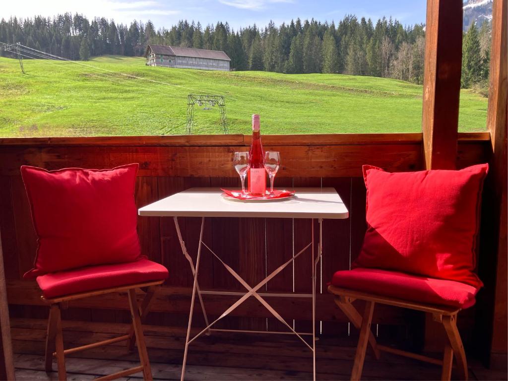 mesa y 2 sillas con mesa y ventana en Ferienwohnung Bergblick am Rande der Wildnis, en Sibratsgfäll