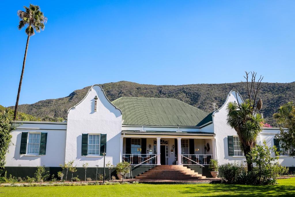 a house with a palm tree and mountains in the background at Altes Landhaus Country Lodge in Oudtshoorn