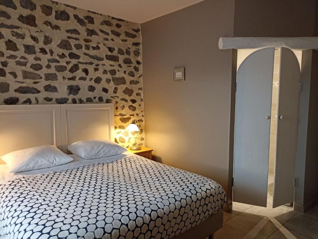 - une chambre avec un lit et un mur en pierre dans l'établissement La Maison de Lili, à Loudes