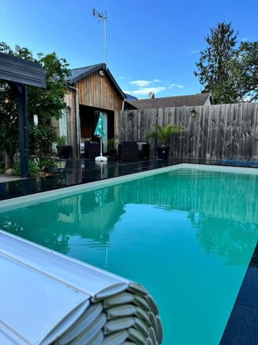 une piscine avec de l'eau bleue dans une cour arrière dans l'établissement Le Petit Bonheur, à Les Ormes