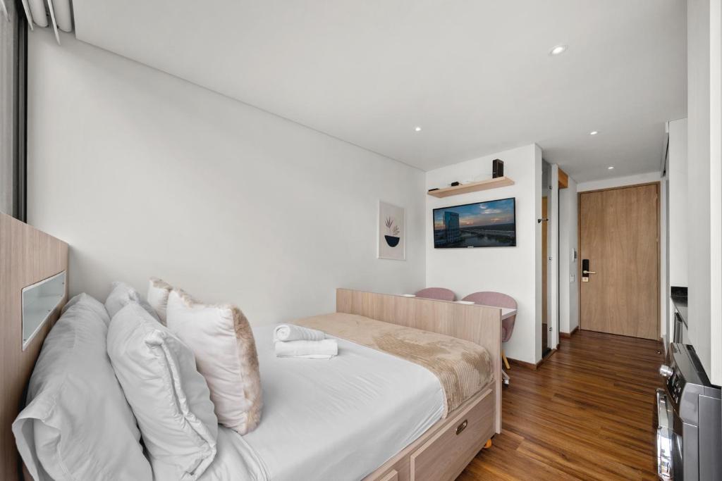 1 dormitorio con 1 cama grande con sábanas blancas en FH - Artsy studio in Chico - Bogota, en Bogotá