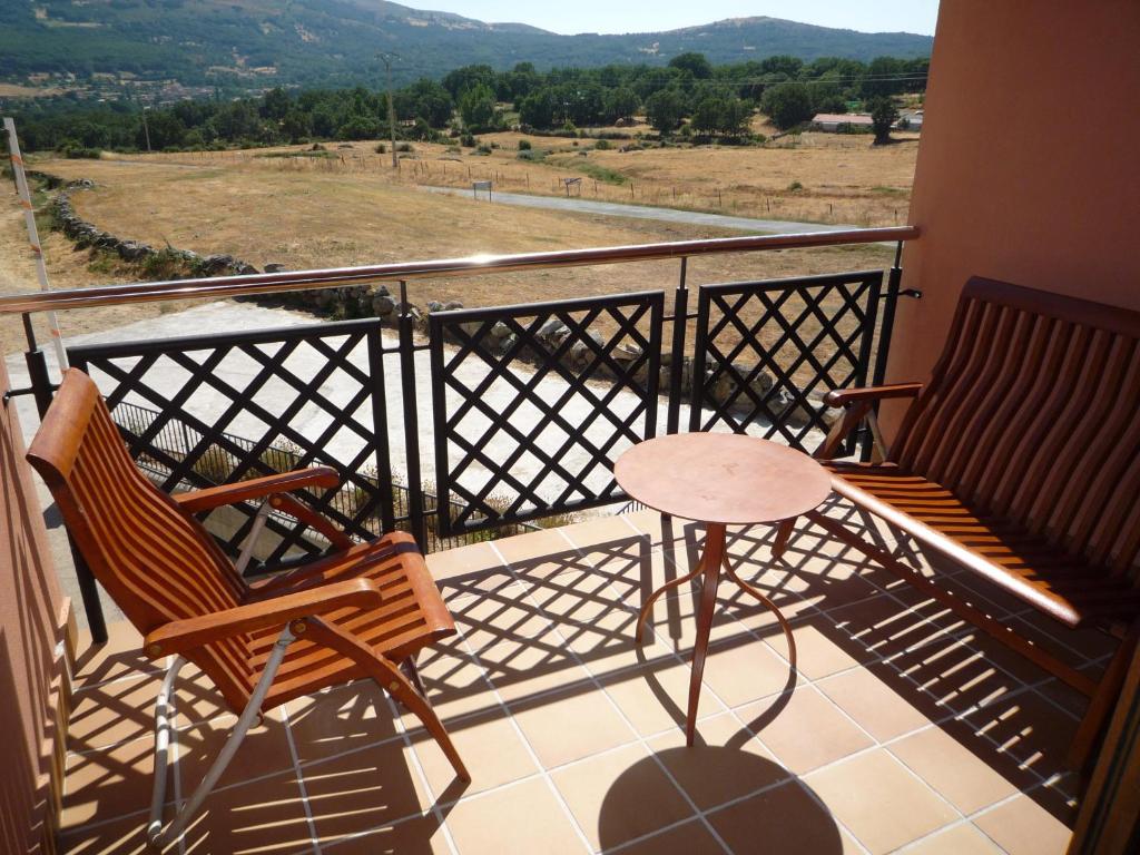 2 sillas y mesa en un balcón con vistas en Apartamentos La Covatilla, en Neila de San Miguel