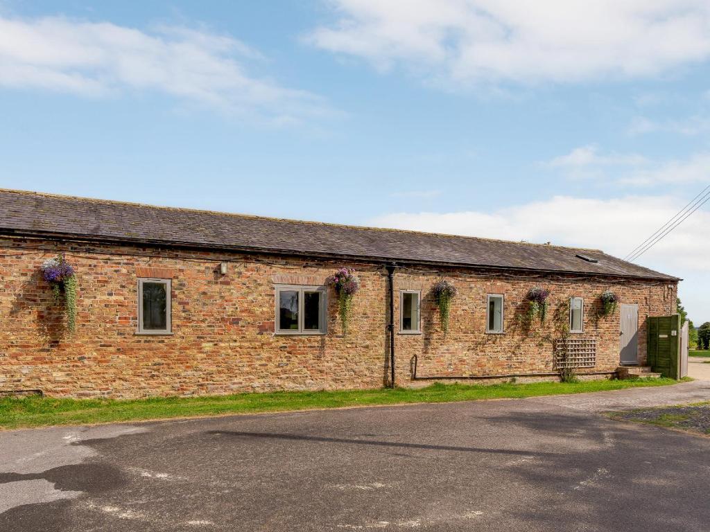 an old brick building with flowers on the windows at Barnby Barn 1 - Uk43808 in Bossall