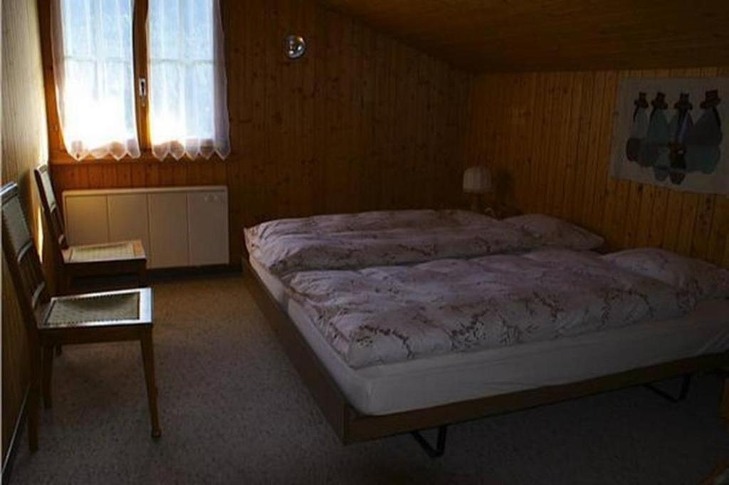 um quarto com uma cama, uma cadeira e uma janela em Tanzhus em Wildhaus