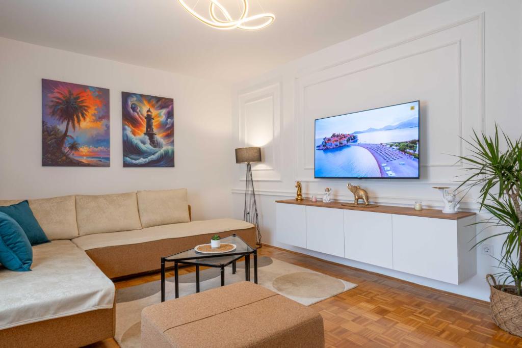 uma sala de estar com um sofá e uma televisão na parede em Apartment UR em Bar