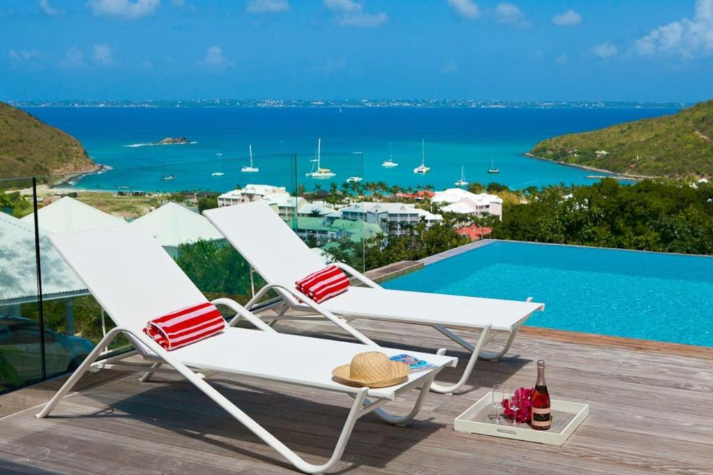 un par de sillas sentadas en una terraza junto a una piscina en Villa Flamboyant, heated swimming pool, sublime view of Anse Marcel, 4 bedrooms en Anse Marcel 
