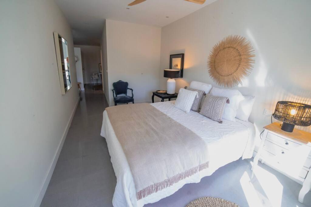 a white bedroom with a large bed and a chair at Exquisito apartamento en el centro. in Gandía