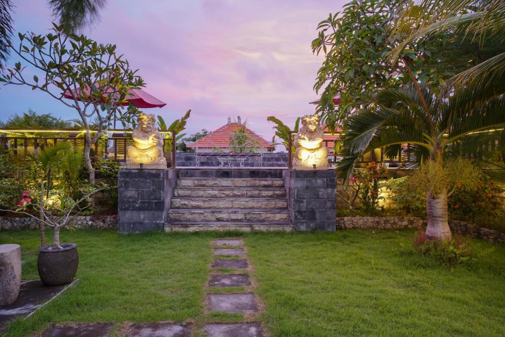 un giardino con due statue di gatti su un muro di Innora Jungle Resort And Spa a Nusa Penida