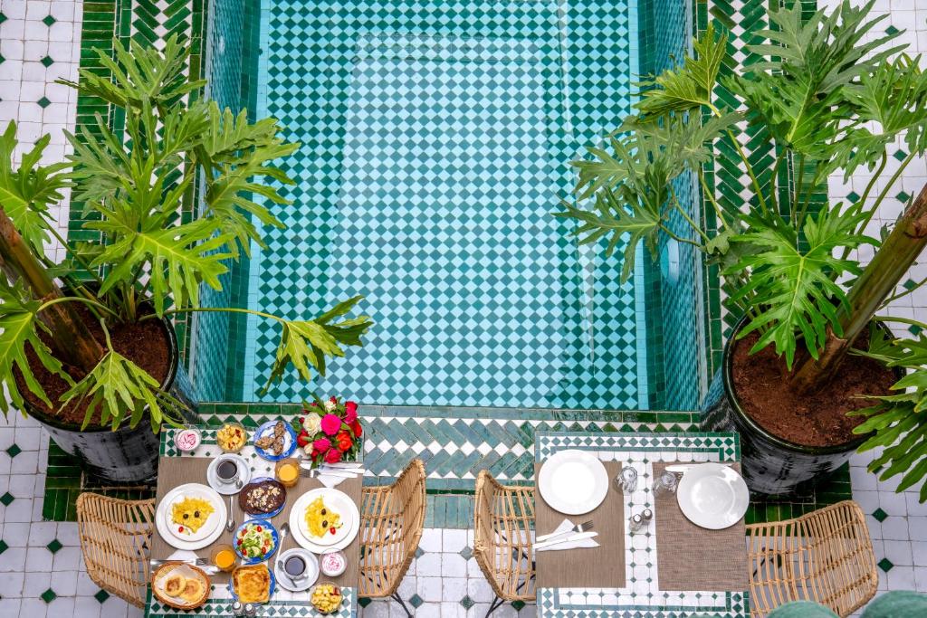 Riad Samir Privilege Boutique Hotel & Spa في مراكش: طاولة مع أطباق من الطعام والنباتات أمام المرآة