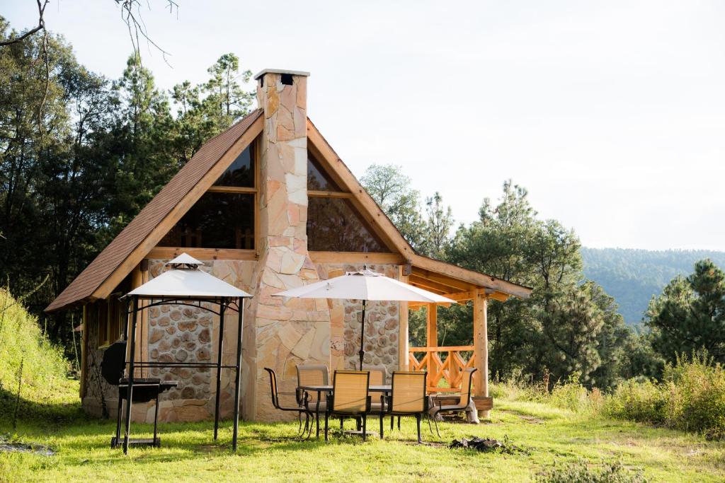 a cabin with a table and chairs and an umbrella at Canto del Bosque Santuario de las luciernagas in Nanacamilpa