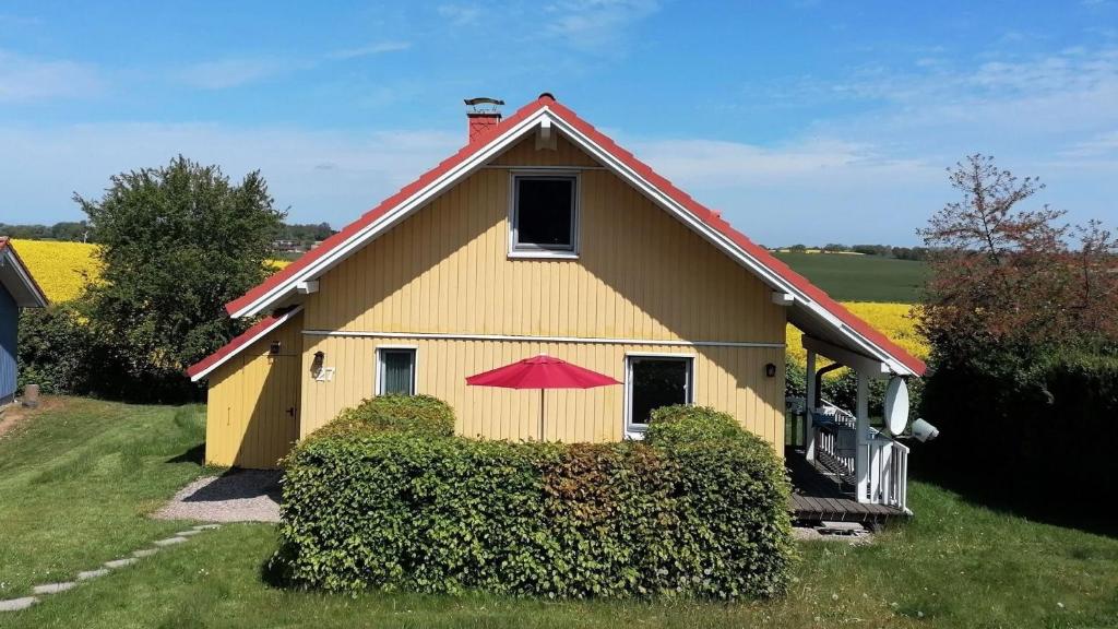 une maison jaune avec un toit rouge et un parapluie rouge dans l'établissement Das magische Geschichtenhaus - Einfach wohlfühlen in der Holsteinischen Schweiz, à Schönwalde am Bungsberg
