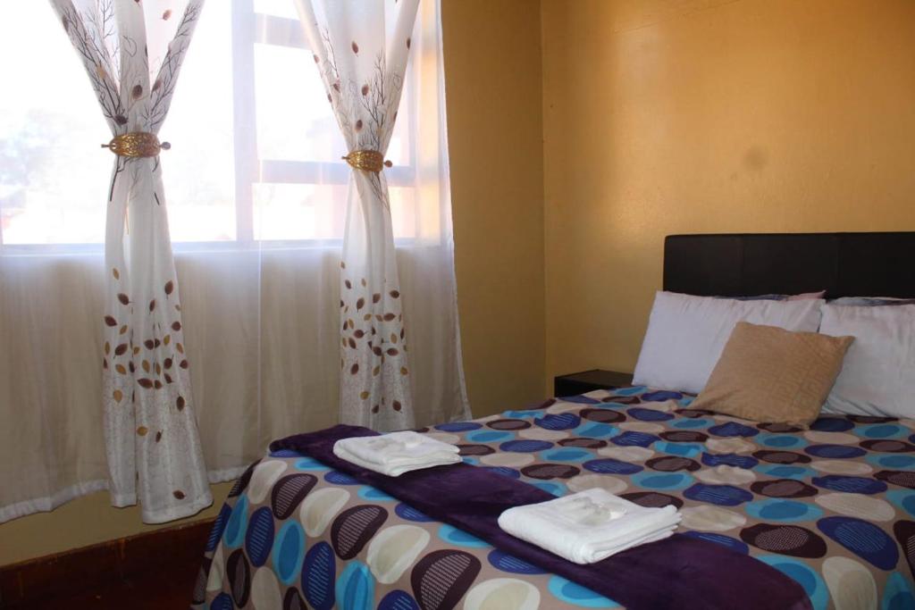 a bedroom with a bed with towels and a window at Macum Guesthouse in Roodepoort