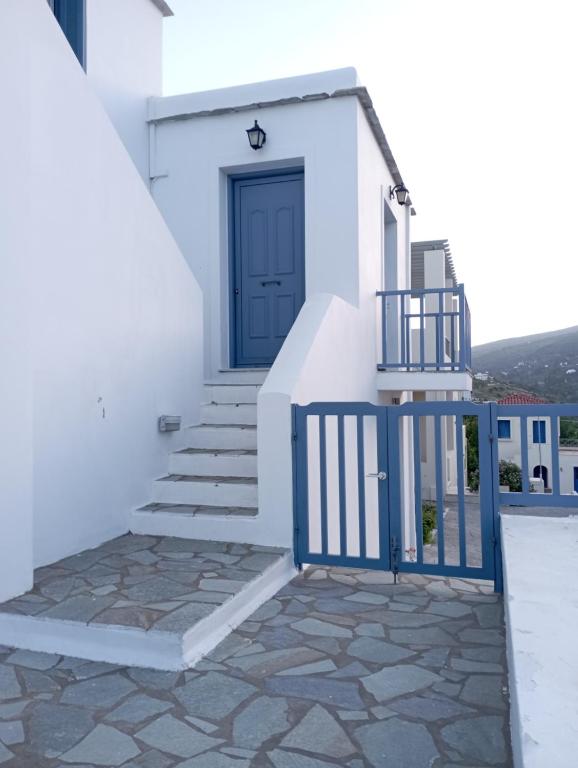 niebieskie drzwi na białym budynku ze schodami w obiekcie Captain's Nest w mieście Andros