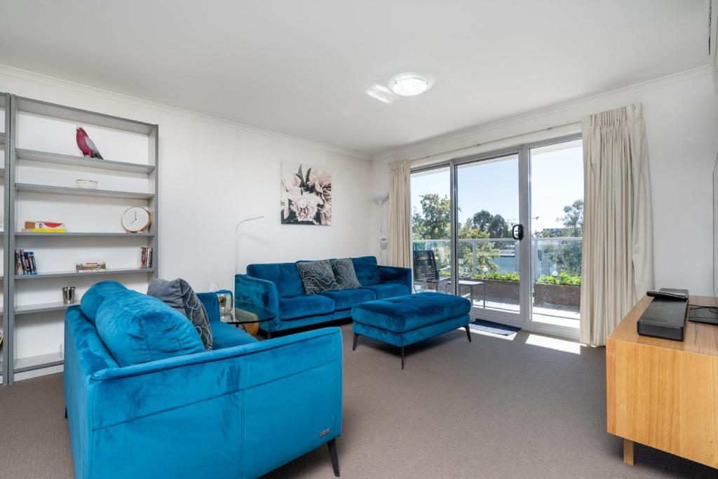 a living room with blue furniture and a large window at Spacious and Cosy Apt with Great Views in Braddon - Hosted by CanStay in Canberra
