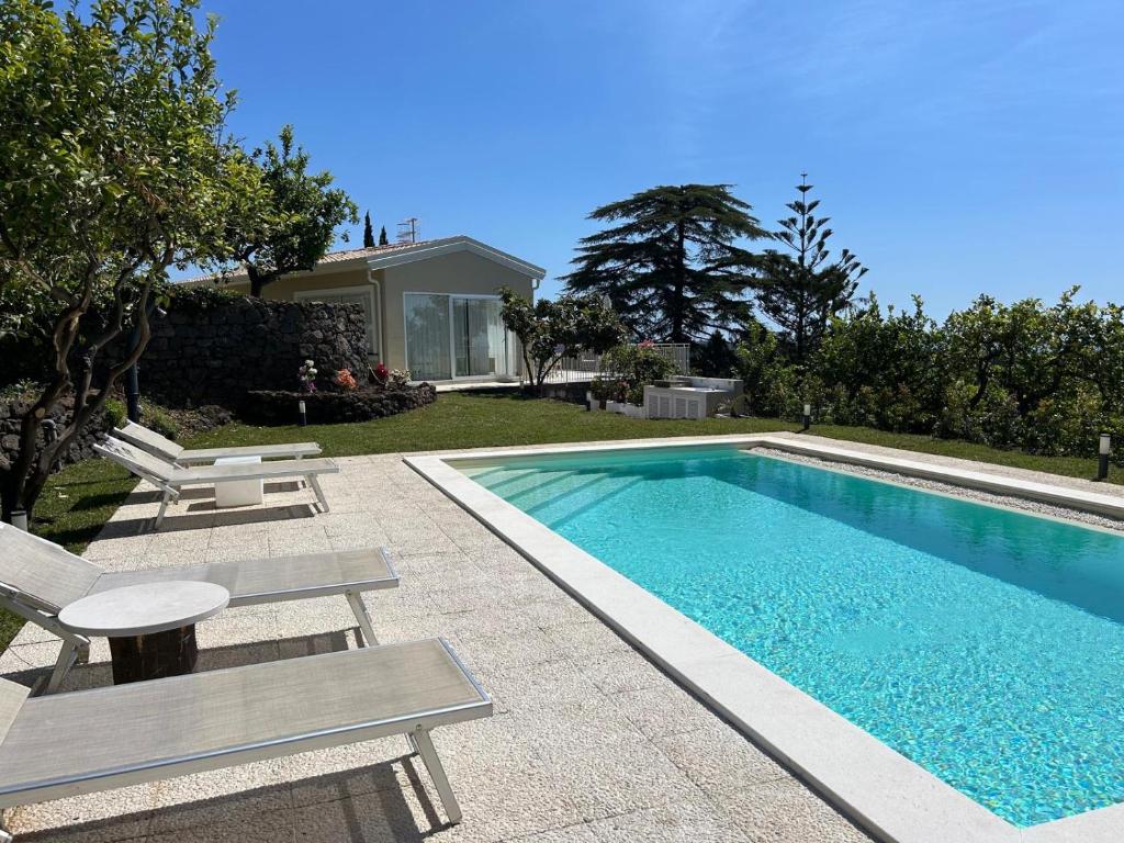 una piscina con 2 sillas y una mesa en Villa Iiulia, en Fiumefreddo di Sicilia