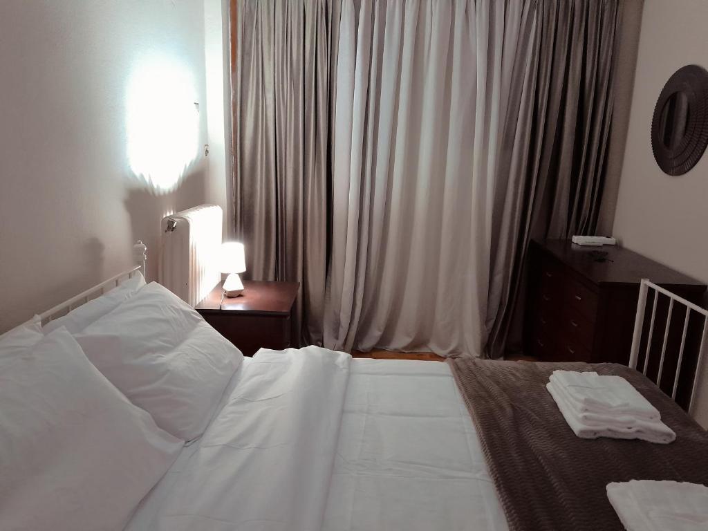 a bedroom with a white bed with a lamp and a window at Spartan Townhouse Apt 3 Leonidas in Sparti