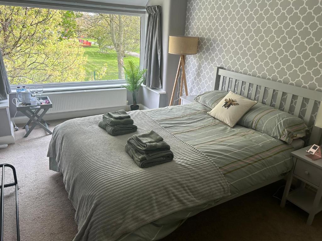 a bedroom with a bed with two towels on it at Lovely, large double bedroom with park view, breakfast in Hazel Grove