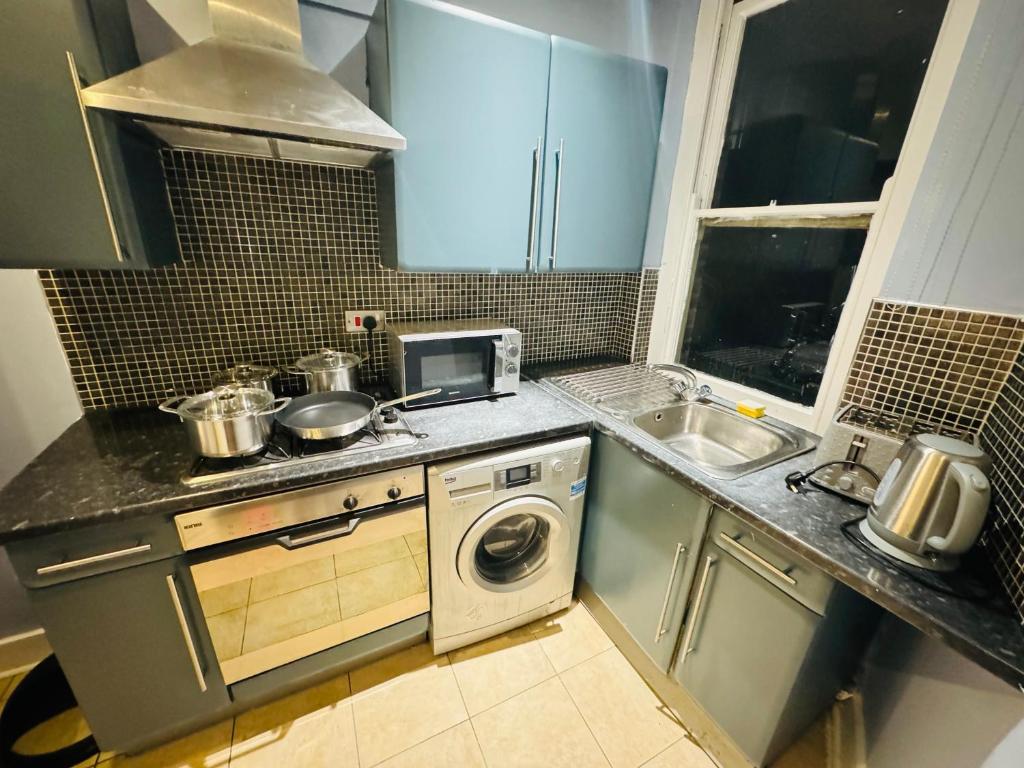 una piccola cucina con lavatrice e lavandino di London Eye 3 Bedroom Apartment a Londra