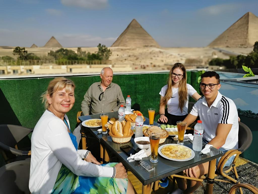 Capital Of Pyramids Hotel في القاهرة: مجموعة من الناس يجلسون على طاولة مع الطعام