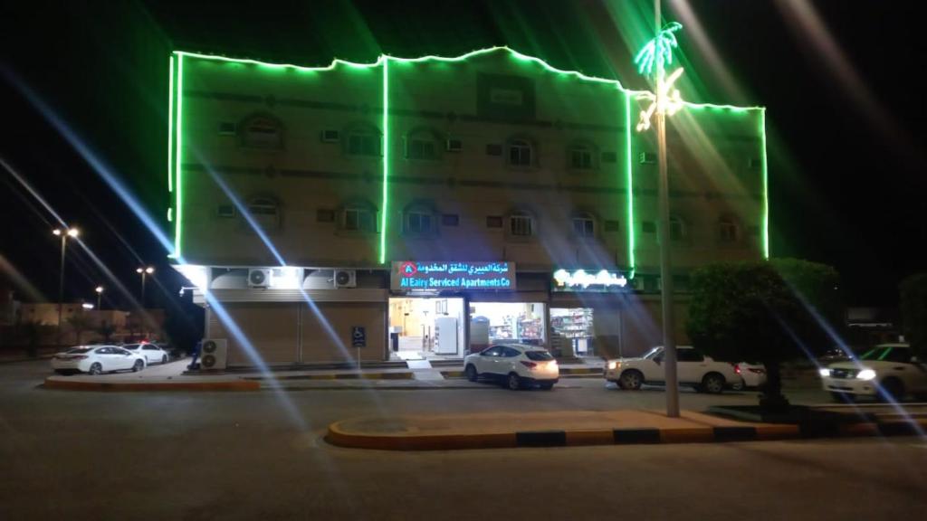 um edifício com carros estacionados num parque de estacionamento à noite em العييري للشقق المفروشة النعيريه 4 em Al Nairyah