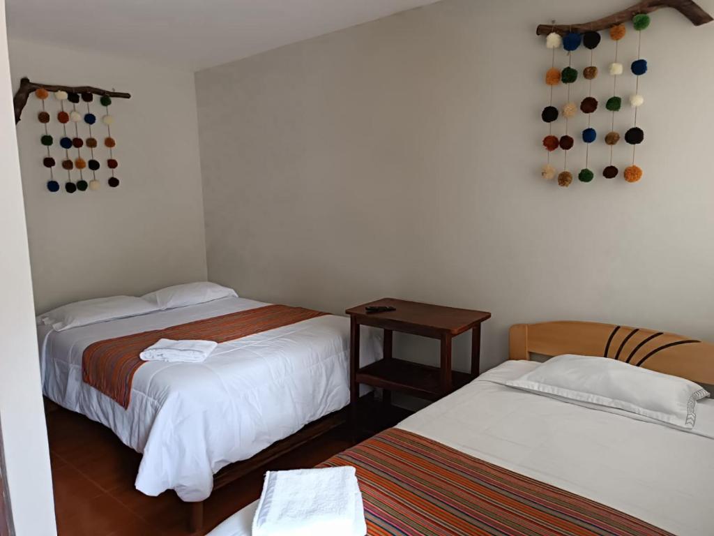 a room with two beds and a table with a table at Hospedaje Quillabamba in Santa Teresa