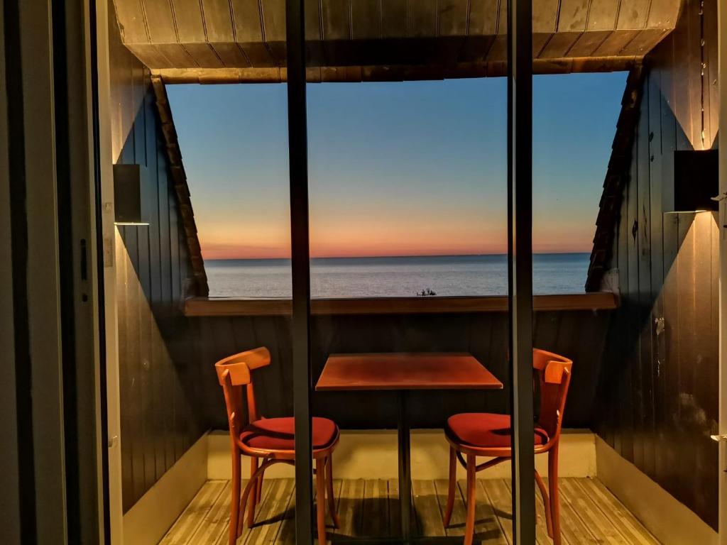 uma mesa e duas cadeiras num quarto com vista para o oceano em Appartement 45m2 - Proche Deauville - Vue Mer em Bénerville-sur-Mer