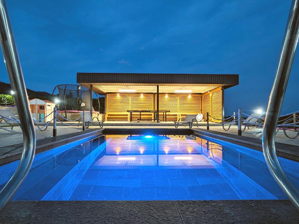 a swimming pool in front of a house at night at Pallos Apartments in Sovata
