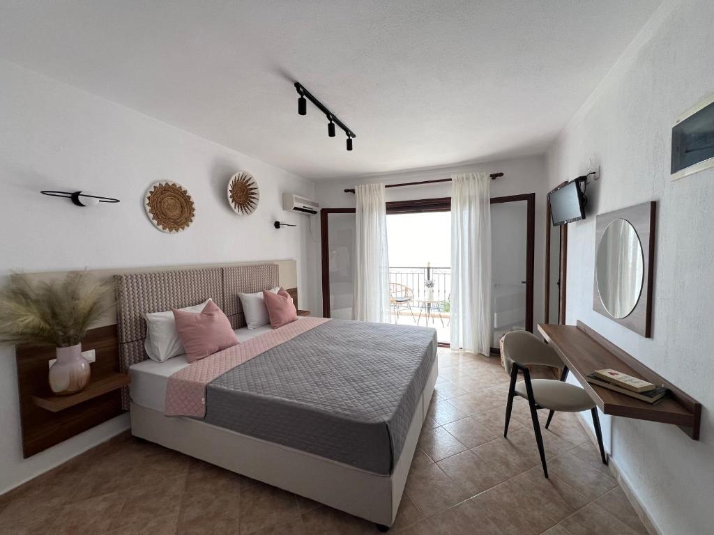 una camera da letto con letto con cuscini rosa e scrivania di Pantheon a Città di Skiathos