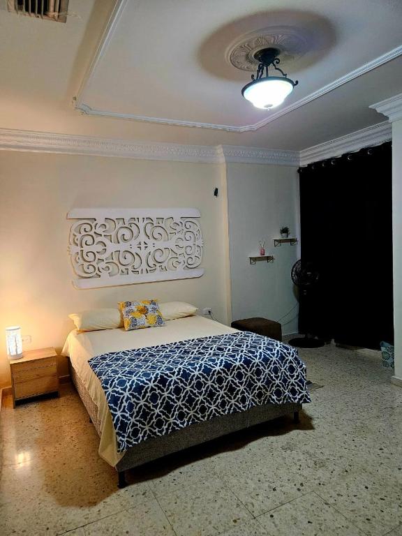 a bedroom with a bed with a blue and white blanket at BLISS HOUSE & spa 92 in Barranquilla