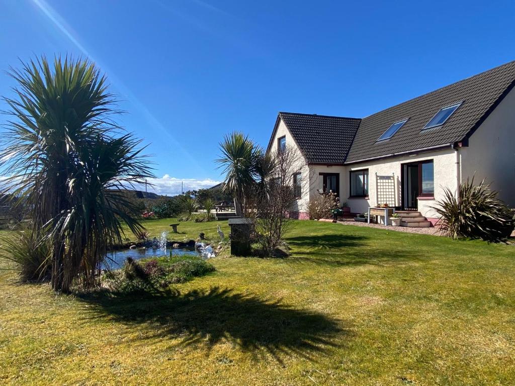 a house with palm trees and a pond in the yard at Little Haven in Gairloch