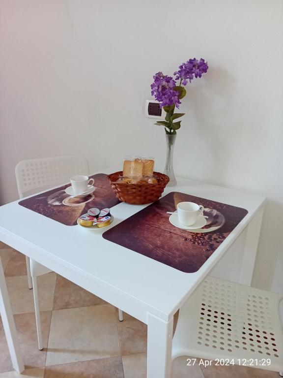 uma mesa branca com um cesto de pão e um vaso de flores em IL GIARDINO em La Spezia