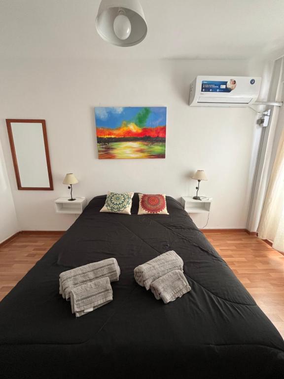 um quarto com uma grande cama preta e 2 almofadas em Rosario centro em Rosário
