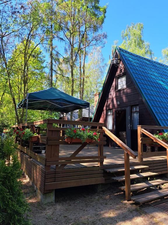a house with a deck and a blue umbrella at Domek Ostrowo in Ostrowo