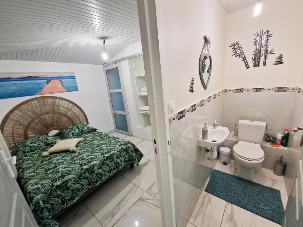 a bedroom with a bed and a toilet and a sink at Plézi Location F3 au bord de mer, Trois-Ilets in Les Trois-Îlets
