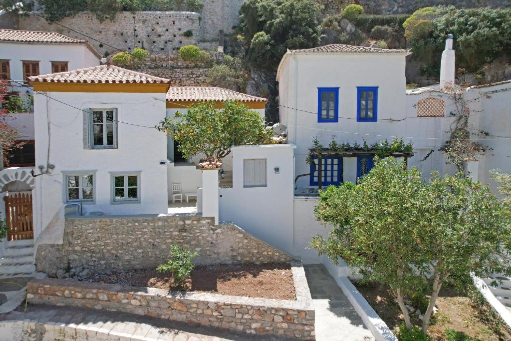 a house with white walls and blue doors at Douskos Citrus Apartments in Hydra