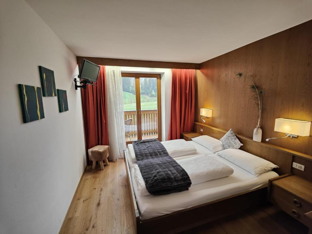 ein Schlafzimmer mit einem Bett in einem Zimmer mit einem Fenster in der Unterkunft Hotel Alpenblick in Sarntal