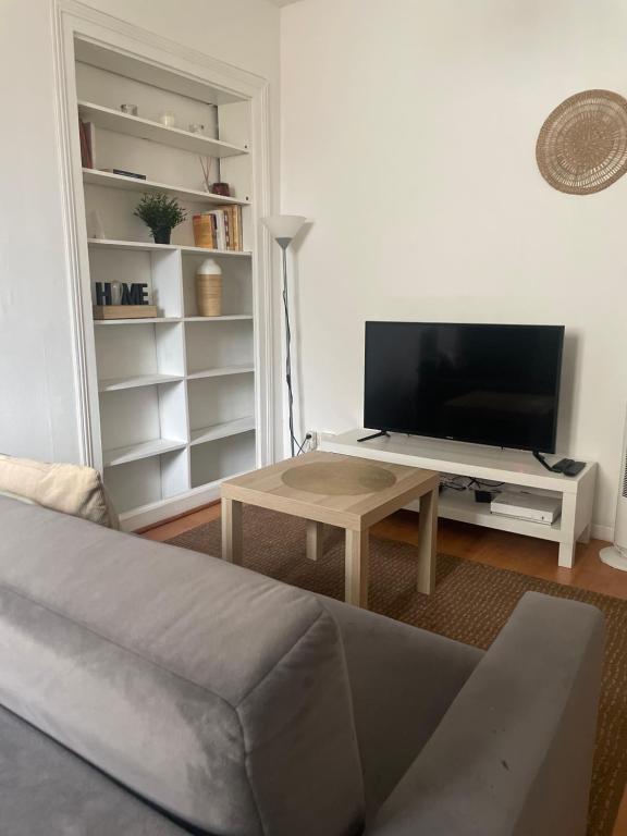 ein Wohnzimmer mit einem Sofa, einem TV und einem Tisch in der Unterkunft Studio cosy Brétigny in Brétigny-sur-Orge