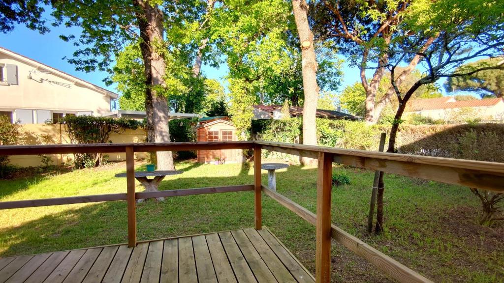 - une terrasse en bois avec une table de pique-nique dans la cour dans l'établissement A l'Ombre du Jardin YourHostHelper, à Saint-Georges-de-Didonne
