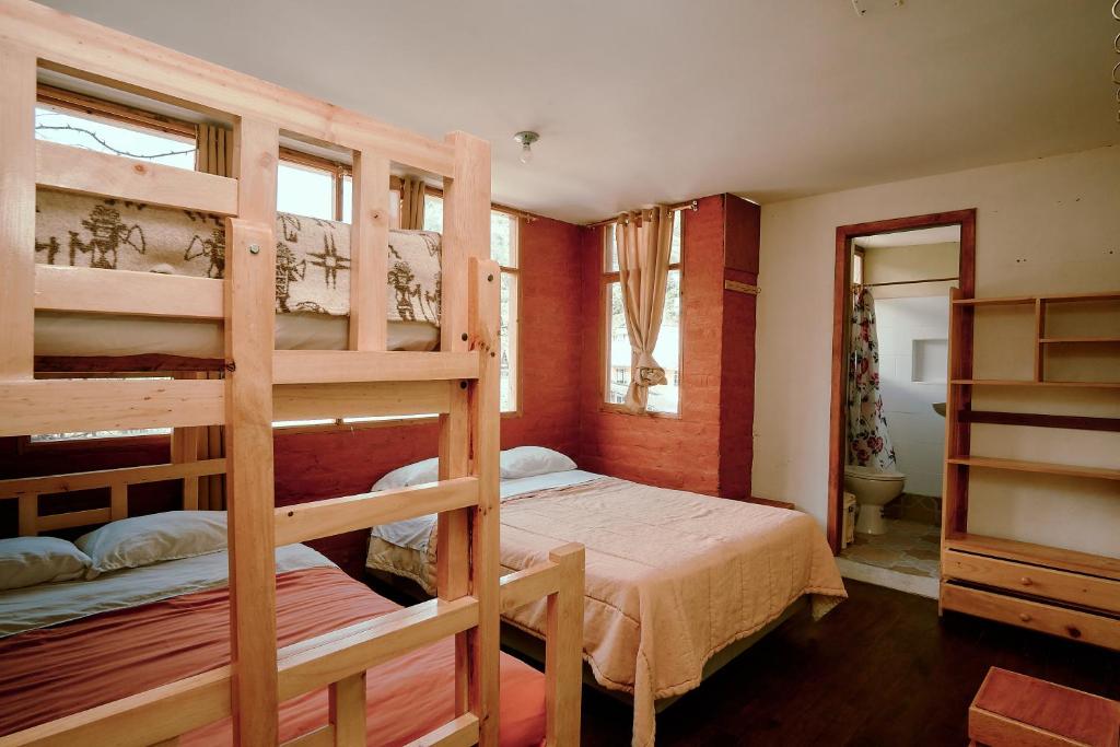 a bedroom with two bunk beds and a bathroom at Backpackers-balcones-river-lodge in Baños