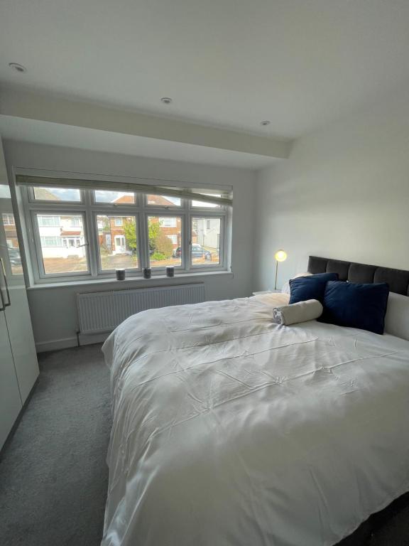 Grey Home Near wembley arena في Wealdstone: سرير أبيض كبير في غرفة نوم مع نوافذ