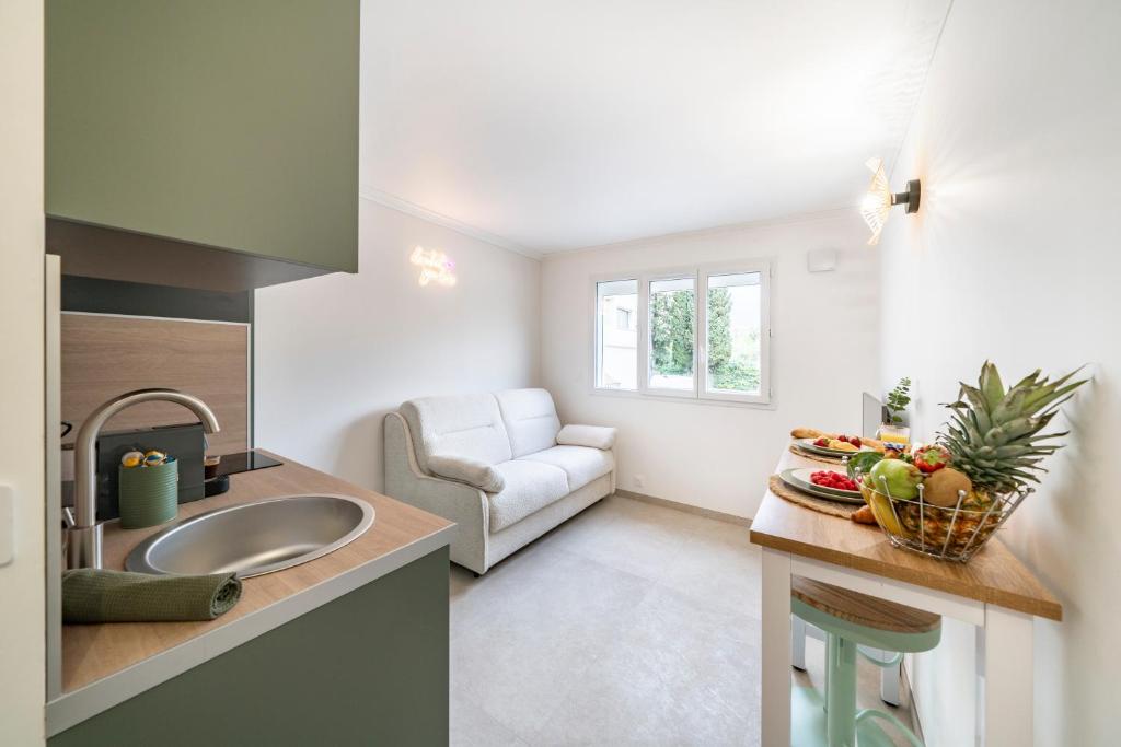 une cuisine avec un évier et un salon dans l'établissement Studio Banane 2 min croisette mitoyen Martinez, à Cannes