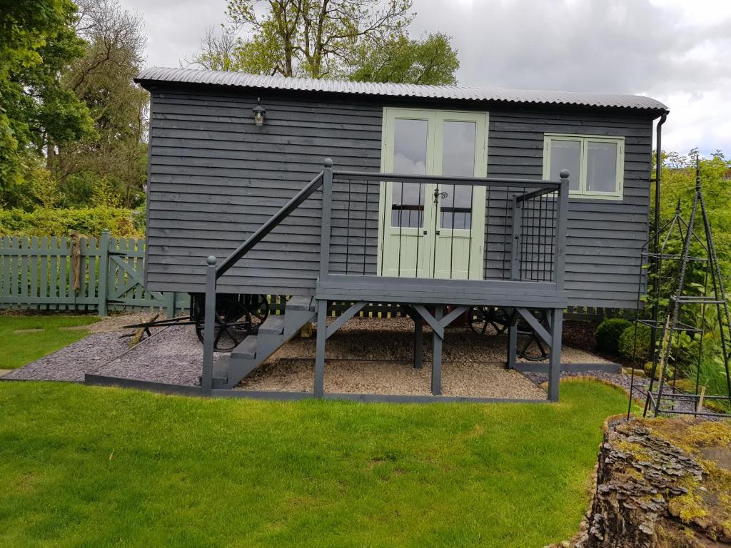 una casa pequeña con una escalera en un patio en Braeside Shepherd's Hut - Greenhead - Hadrian's Wall - Northumberland, en Greenhead