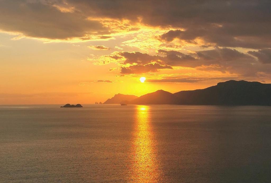 um pôr-do-sol sobre o oceano com o pôr-do-sol em Path of gods em Pianillo