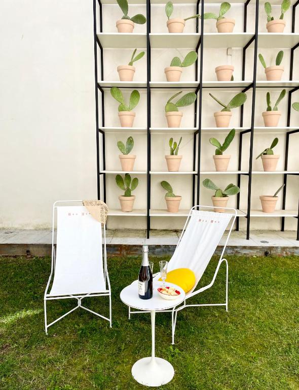 deux chaises et une table avec une bouteille de vin sur l'herbe dans l'établissement VILMA appartement luxe, à Carcassonne