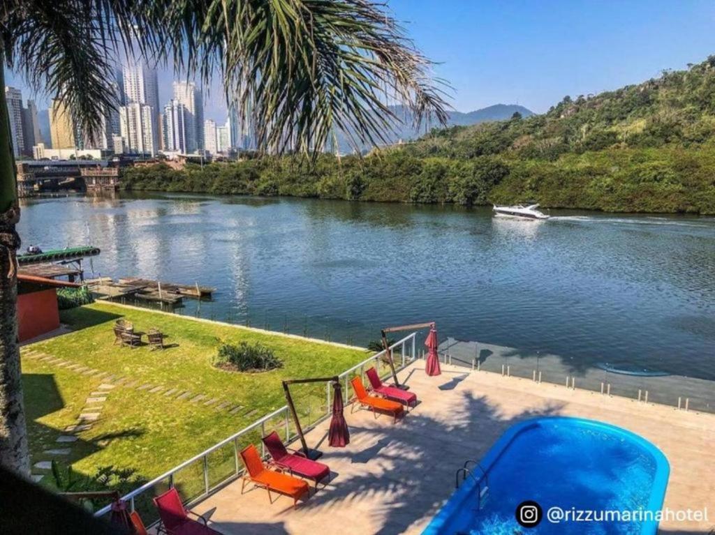 vista para um rio com um grupo de cadeiras em Rizzu Marina Hotel em Balneário Camboriú