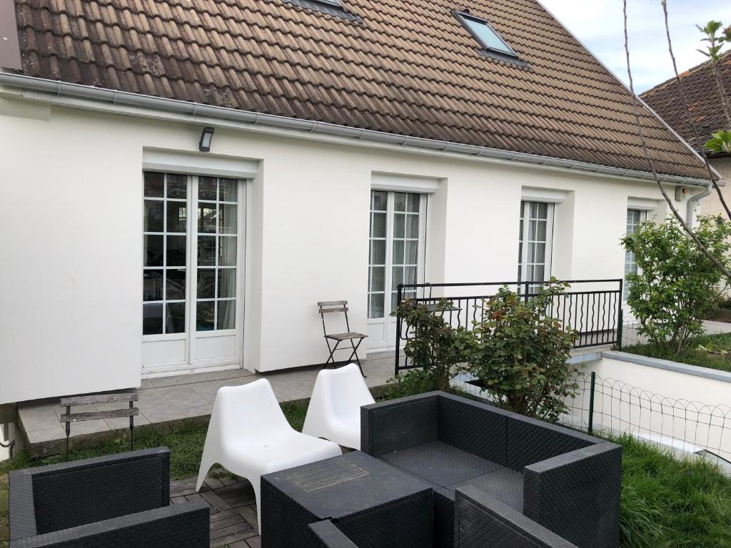 a white house with a patio with white chairs at Helene in Torcy