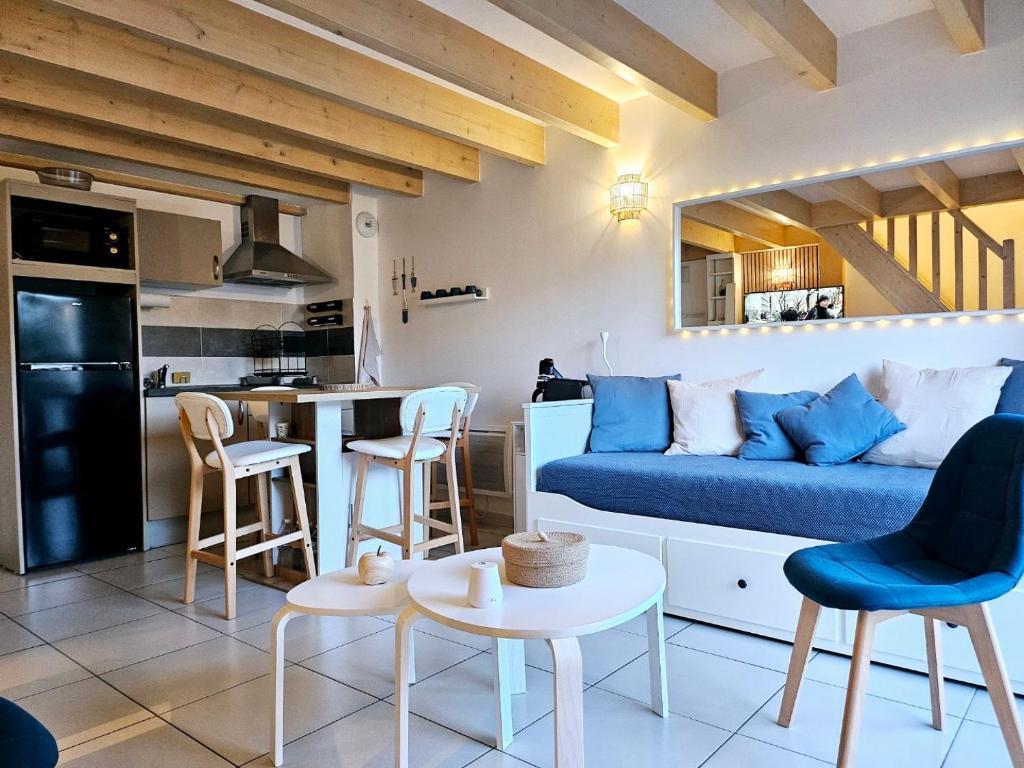 un salon avec un canapé bleu et une cuisine dans l'établissement Appartement cosy près de l’océan, à Royan